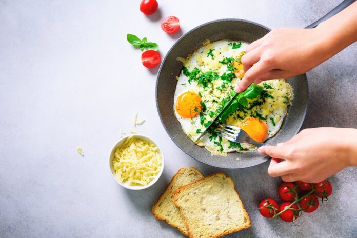 Girl,Hands,Above,Frying,Pan,With,Three,Cooked,Eggs,,Herbs,